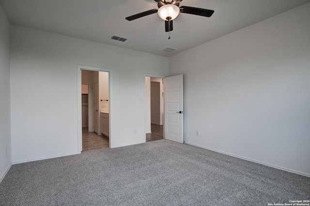 unfurnished bedroom with ensuite bathroom, light carpet, and ceiling fan