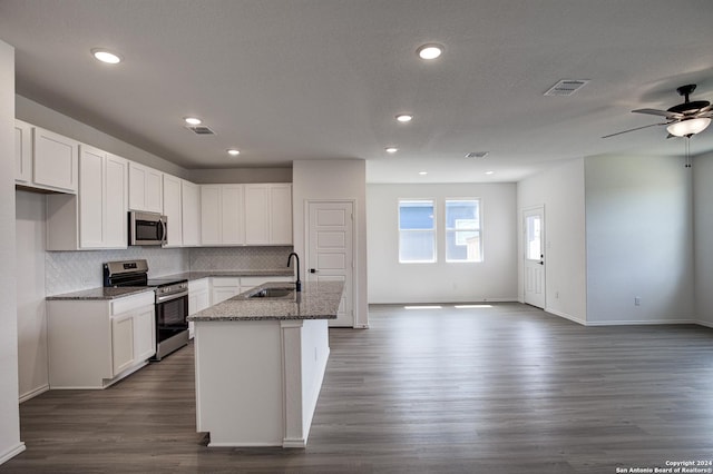 kitchen with stainless steel appliances, a center island with sink, white cabinets, and light stone counters