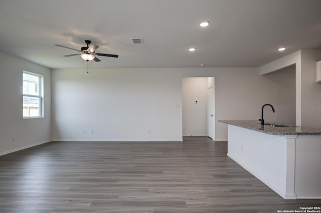 kitchen featuring dark wood-type flooring, sink, light stone counters, ceiling fan, and white cabinets