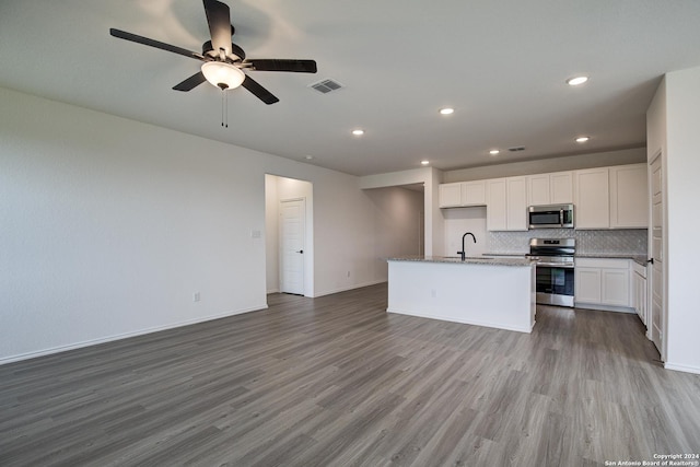 kitchen with white cabinetry, hardwood / wood-style floors, backsplash, stainless steel appliances, and an island with sink