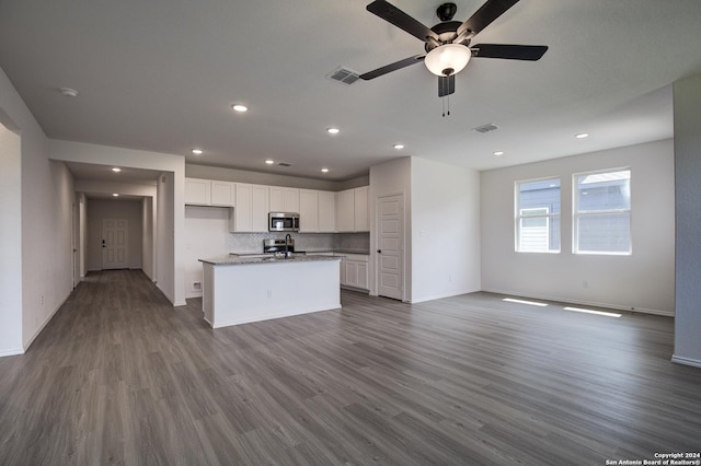 kitchen featuring hardwood / wood-style floors, an island with sink, white cabinets, decorative backsplash, and ceiling fan