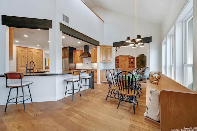 dining area with light hardwood / wood-style floors, sink, high vaulted ceiling, and a chandelier