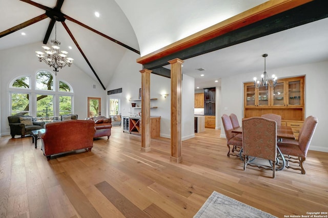 dining space featuring a chandelier, high vaulted ceiling, decorative columns, and light wood-type flooring