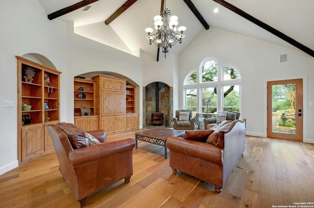 living room with light hardwood / wood-style floors, beam ceiling, a notable chandelier, built in shelves, and high vaulted ceiling