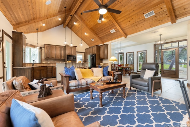 living room with high vaulted ceiling, beam ceiling, ceiling fan with notable chandelier, and light tile floors