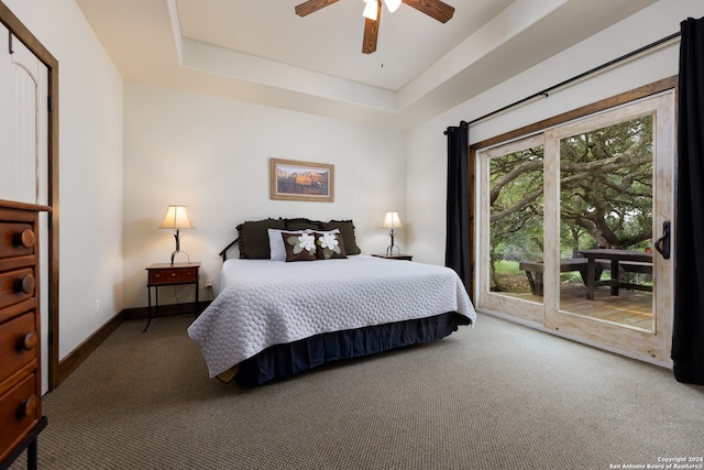 carpeted bedroom featuring access to exterior, ceiling fan, and a raised ceiling