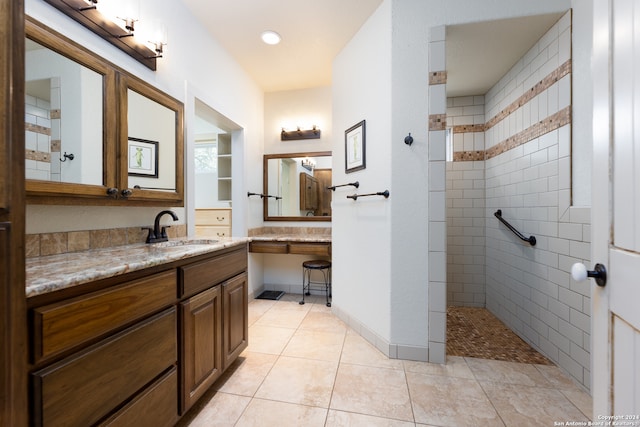 bathroom with a tile shower, tile flooring, and vanity