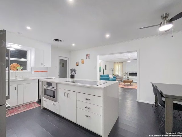 kitchen featuring white cabinets, black electric stovetop, dark hardwood / wood-style floors, stainless steel oven, and ceiling fan