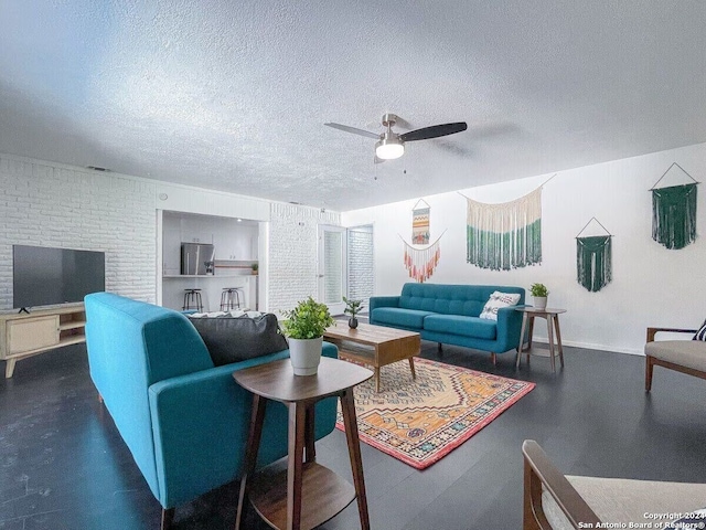 living room featuring a textured ceiling, a fireplace, ceiling fan, and brick wall