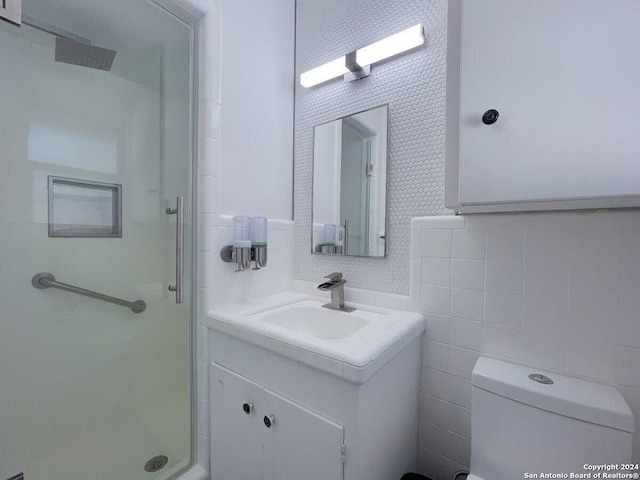 bathroom with tile walls, large vanity, toilet, and walk in shower