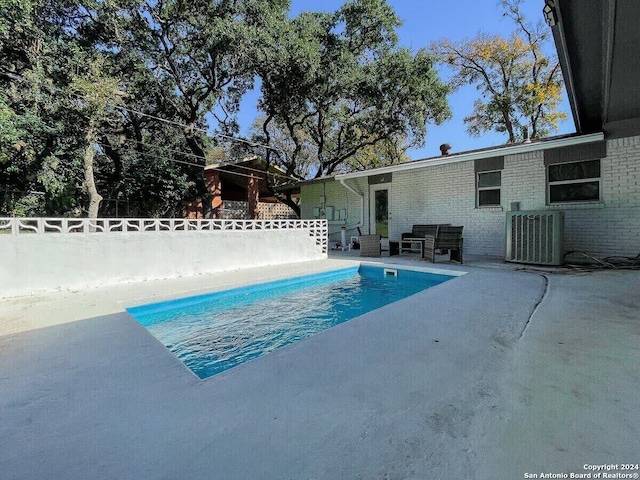 view of swimming pool featuring a patio and central air condition unit