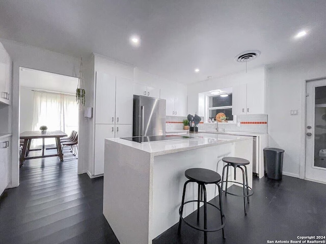 kitchen with backsplash, dark hardwood / wood-style floors, stainless steel fridge, and white cabinetry