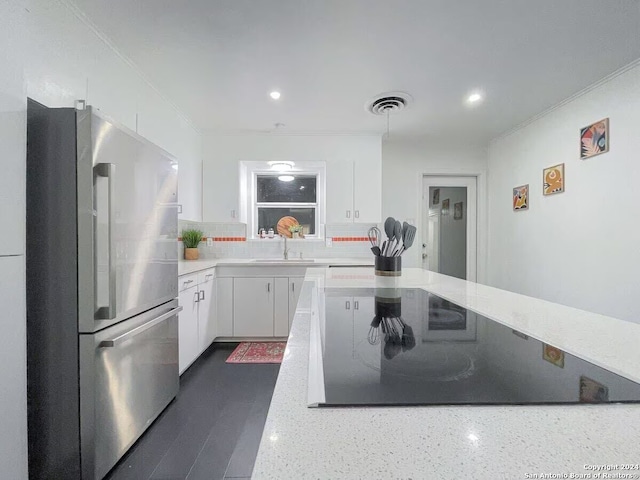 kitchen with light stone countertops, white cabinetry, sink, tasteful backsplash, and stainless steel fridge