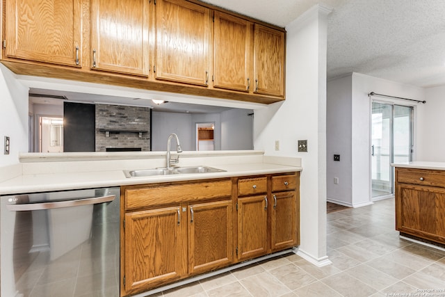 kitchen with sink, dishwasher, light tile floors, and a textured ceiling