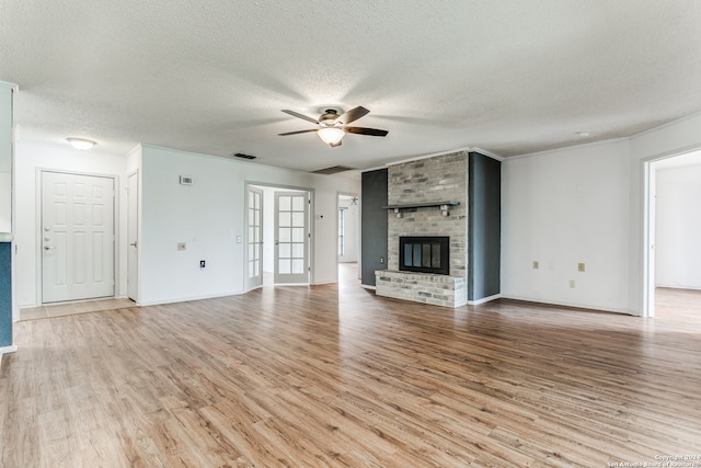 unfurnished living room with a brick fireplace, ceiling fan, a textured ceiling, and light wood-type flooring