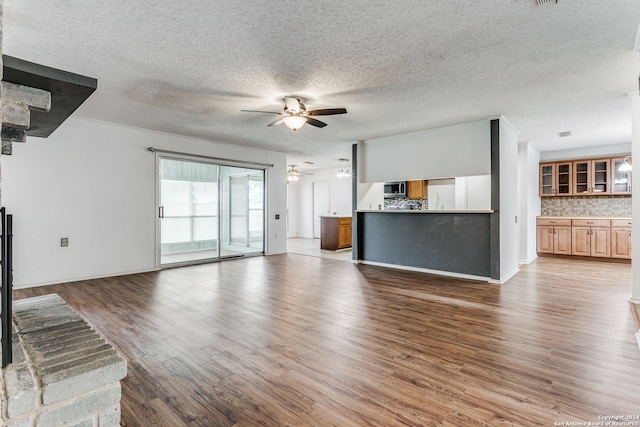 unfurnished living room featuring dark wood-type flooring, ceiling fan, and a textured ceiling