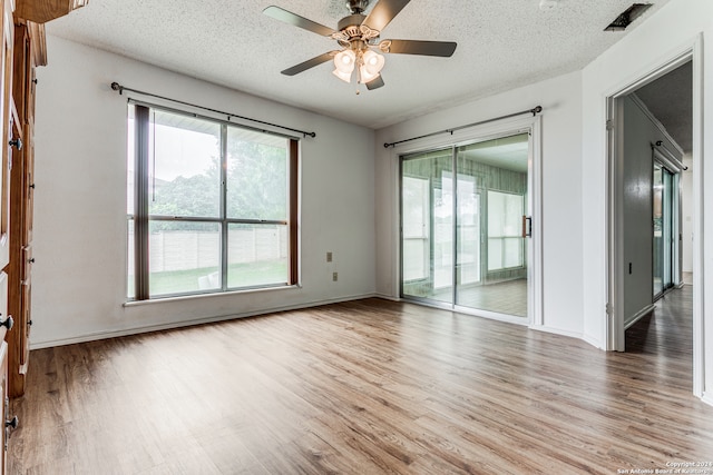 spare room featuring light hardwood / wood-style floors, ceiling fan, and a textured ceiling