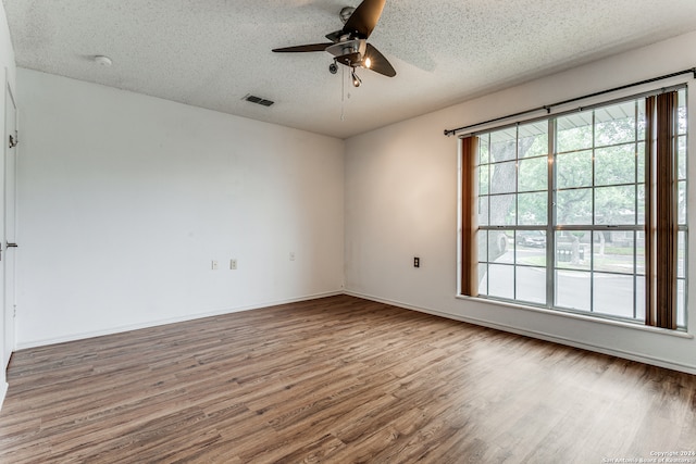 unfurnished room featuring plenty of natural light, light hardwood / wood-style floors, ceiling fan, and a textured ceiling