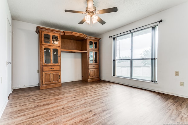 unfurnished living room with light hardwood / wood-style flooring, ceiling fan, and a textured ceiling