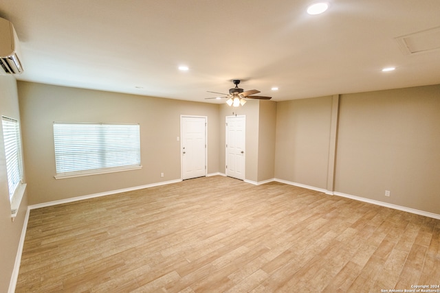 empty room featuring a wealth of natural light, a wall unit AC, and light wood-type flooring