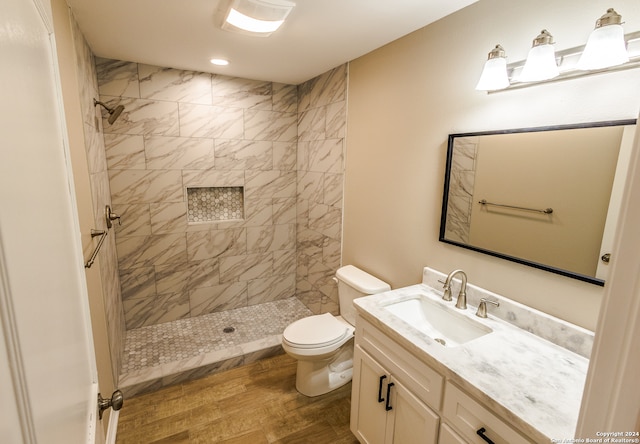 bathroom with vanity, hardwood / wood-style floors, toilet, and a tile shower