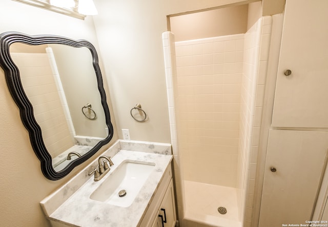 bathroom with tiled shower and vanity