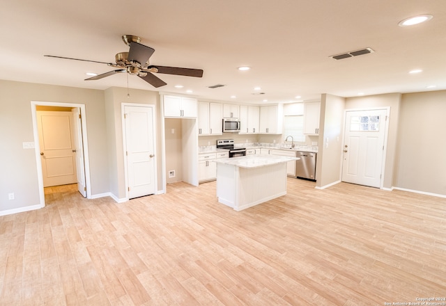 kitchen with sink, white cabinetry, light hardwood / wood-style flooring, a kitchen island, and stainless steel appliances