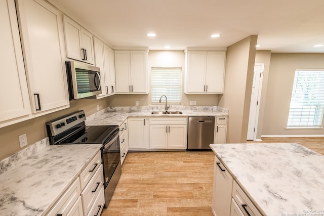 kitchen with white cabinetry, sink, light stone countertops, and appliances with stainless steel finishes