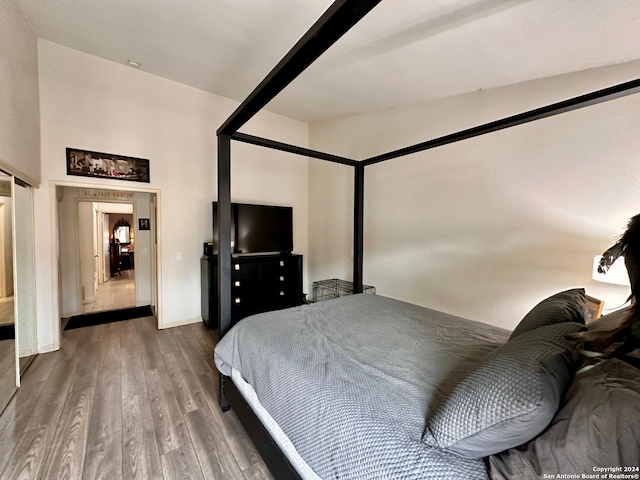 bedroom with high vaulted ceiling and dark wood-type flooring