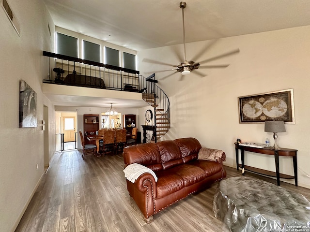 living room featuring ceiling fan with notable chandelier, dark wood-type flooring, and a towering ceiling