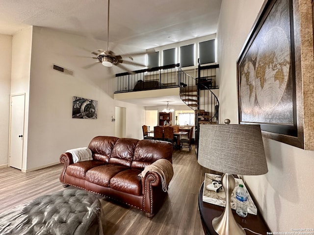 living room featuring ceiling fan with notable chandelier, dark hardwood / wood-style flooring, and a high ceiling