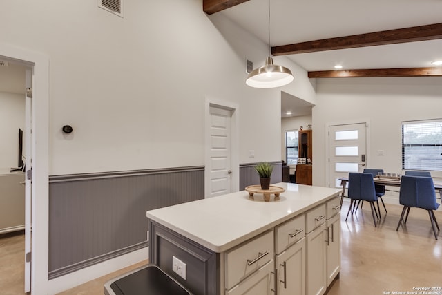 kitchen with a wealth of natural light, hanging light fixtures, beamed ceiling, and a kitchen island