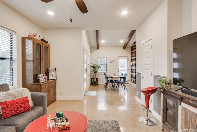 living room with a healthy amount of sunlight, beam ceiling, and ceiling fan