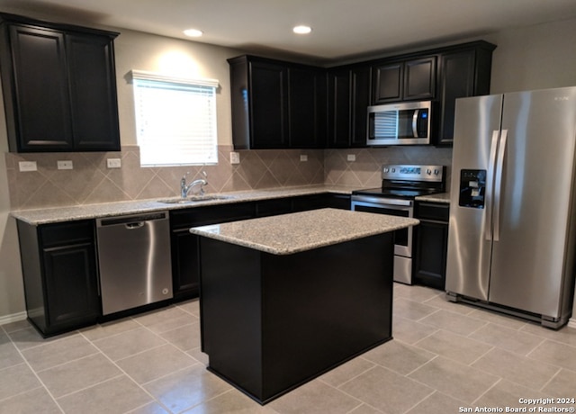 kitchen featuring tasteful backsplash, light tile flooring, a center island, sink, and appliances with stainless steel finishes