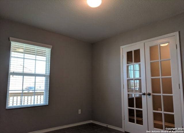 spare room with dark tile flooring and french doors