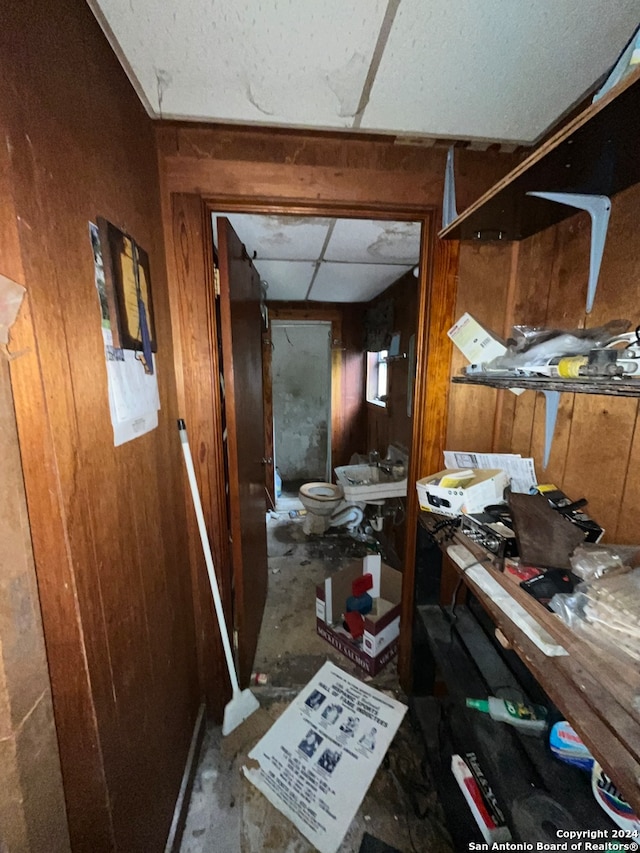 misc room with a paneled ceiling and wooden walls
