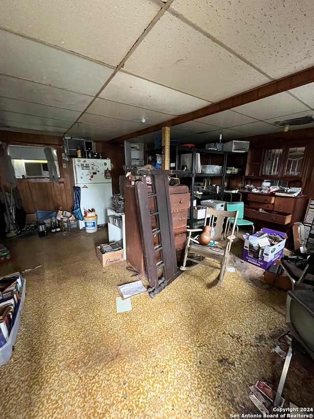 basement featuring a paneled ceiling and white refrigerator