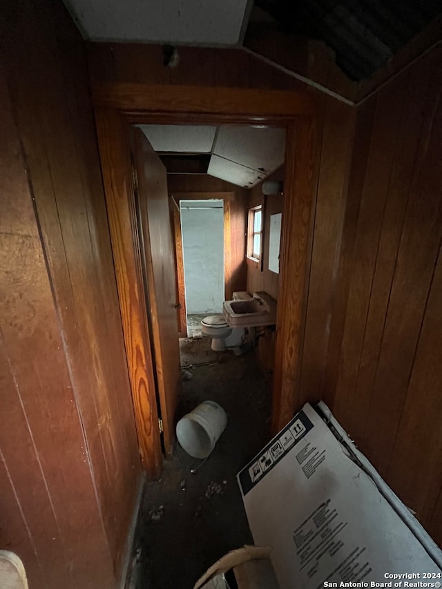 interior space with lofted ceiling, sink, and wooden walls