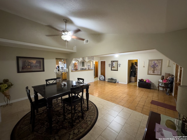 tiled dining space featuring lofted ceiling, ceiling fan, and a textured ceiling