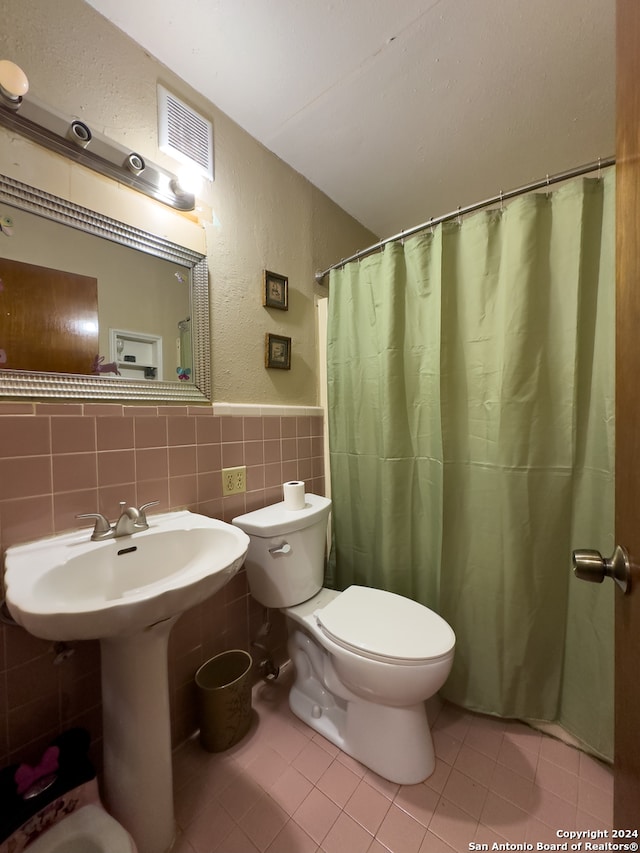 bathroom with tile flooring, tasteful backsplash, toilet, and tile walls