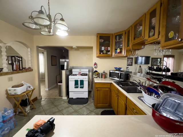 kitchen with light tile floors, white gas range oven, sink, decorative light fixtures, and an inviting chandelier