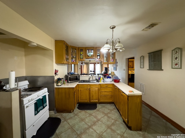 kitchen featuring pendant lighting, kitchen peninsula, gas range gas stove, a notable chandelier, and light tile floors