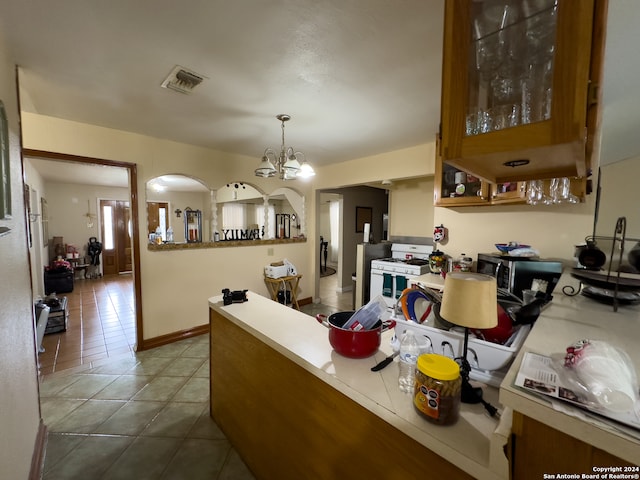 kitchen featuring hanging light fixtures, white gas range, a chandelier, and tile floors