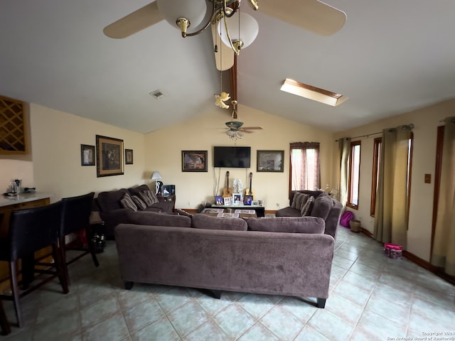 tiled living room with ceiling fan and vaulted ceiling with skylight