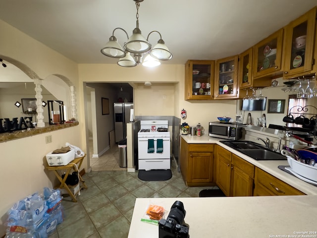 kitchen with light tile floors, sink, a chandelier, stainless steel appliances, and pendant lighting