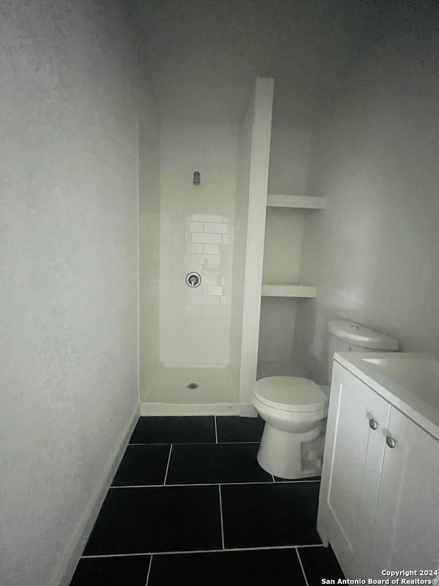 bathroom featuring a shower, vanity, toilet, and tile flooring