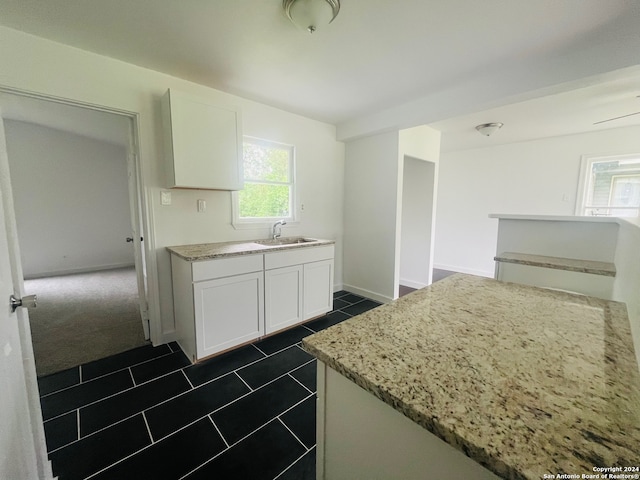 kitchen with light stone counters, dark tile flooring, and white cabinetry