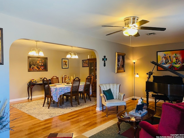 living room with ceiling fan with notable chandelier and hardwood / wood-style flooring