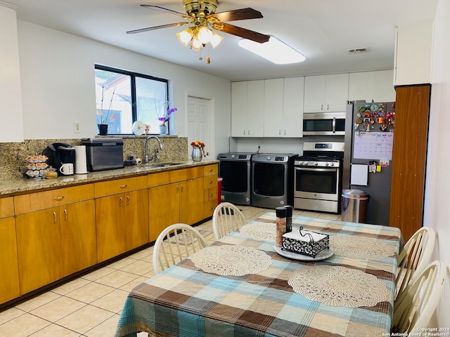 kitchen with white cabinetry, washer and clothes dryer, ceiling fan, appliances with stainless steel finishes, and sink