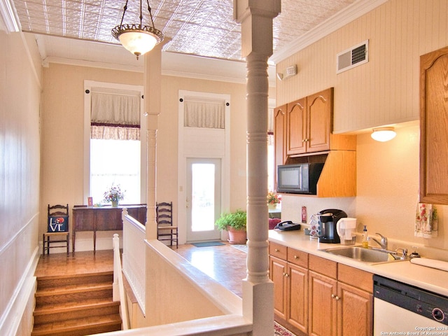 kitchen featuring white dishwasher, sink, ornamental molding, and decorative columns